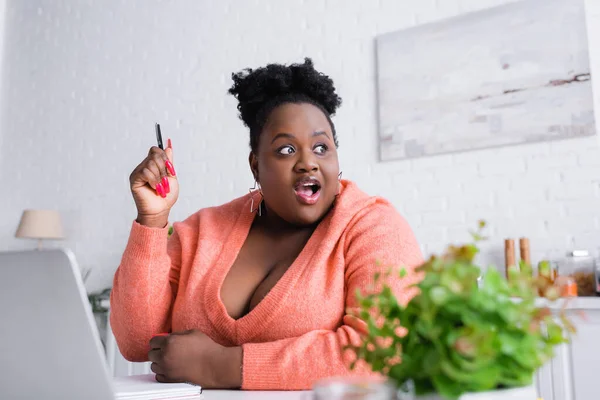 Amazed african american plus size freelancer looking away at home — Stock Photo