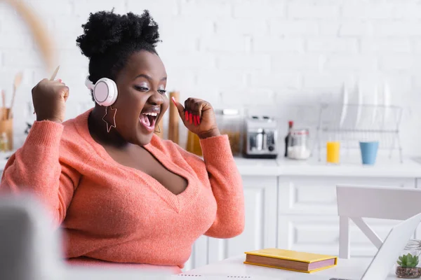 Amazed african american plus size woman listening podcast in headphones — Stock Photo