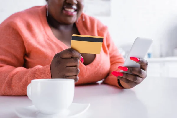 Abgeschnittene Ansicht einer glücklichen afrikanisch-amerikanischen Plus-Size-Frau mit Kreditkarte und Smartphone — Stockfoto