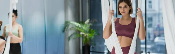 Sportswoman positivo aquecimento com rede de ioga aérea no fundo borrado, banner — Fotografia de Stock