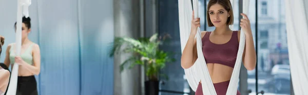 Deportista positiva que calienta con la hamaca aérea del yoga en fondo borroso, bandera - foto de stock