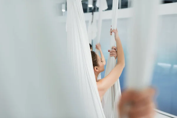 Selective focus of young woman practicing fly yoga on blurred foreground — Stock Photo