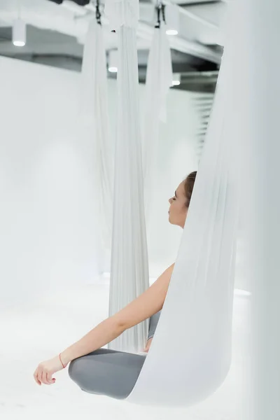 Jovem mulher meditando em rede de ioga aérea em pose de lótus — Fotografia de Stock