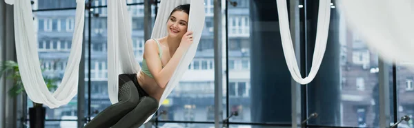 Smiling woman looking away while relaxing in aerial yoga hammock, banner — Stock Photo