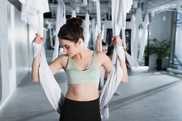 Bella donna riscaldamento con cinghia yoga aerea su sfondo sfocato — Foto stock