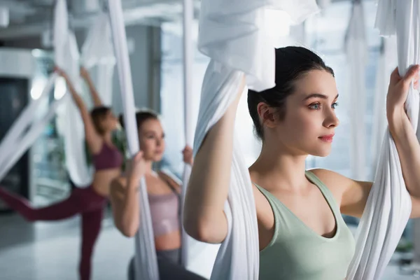 Красивая спортсменка растягивает руки с воздушным ремнем для йоги в фитнес-центре — стоковое фото