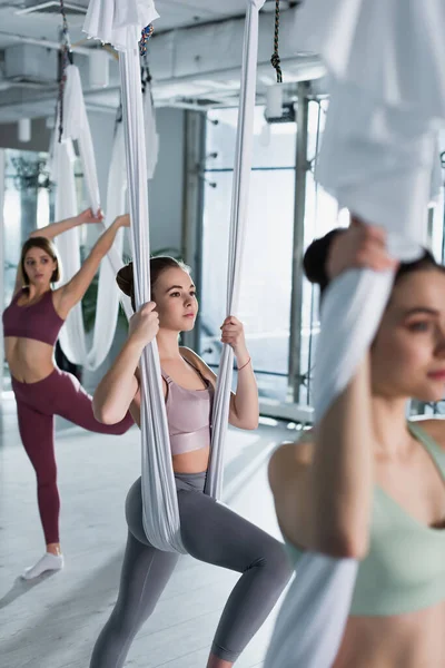 Jóvenes deportistas haciendo ejercicio con correas de yoga con mosca en el centro deportivo, borrosa en primer plano - foto de stock