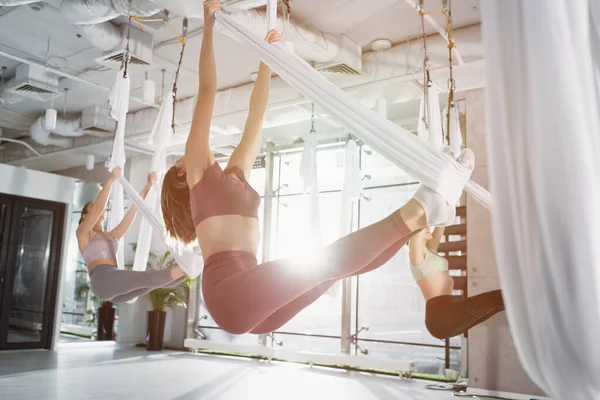 Grupo de mujeres deportivas que practican yoga aéreo en un centro deportivo - foto de stock