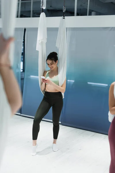 Enfoque selectivo de mensajería de mujer deportiva en el teléfono inteligente durante el entrenamiento de yoga con mosca - foto de stock