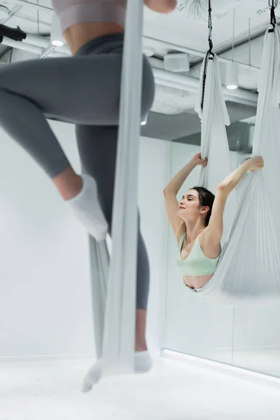 Bastante deportista haciendo ejercicio con correas durante el fly yoga en el centro deportivo - foto de stock