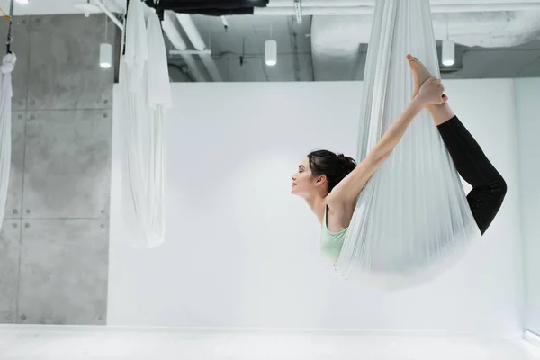 Vista lateral de mujer estirándose con correas de yoga fly - foto de stock