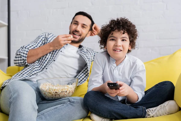 Alegre árabe padre e hijo viendo comedia película en casa - foto de stock