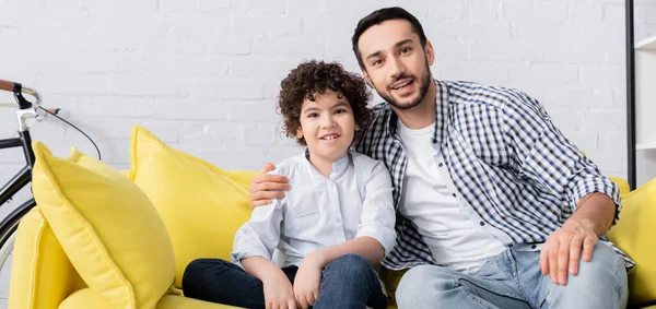 Junger muslimischer Mann umarmt glücklichen Sohn, während er in die Kamera blickt, Banner — Stockfoto