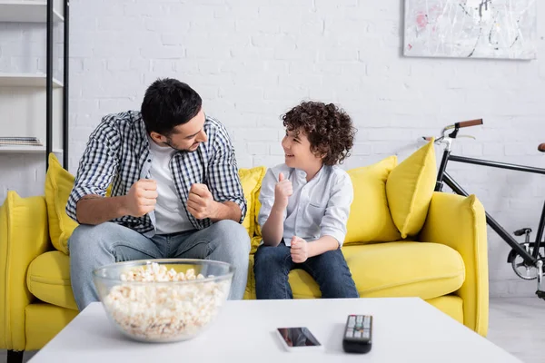 Happy arabian father showing success gesture while talking to cheerful son — Stock Photo