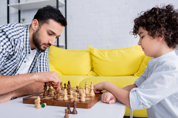 Arabian man playing chess with son at home — Stock Photo