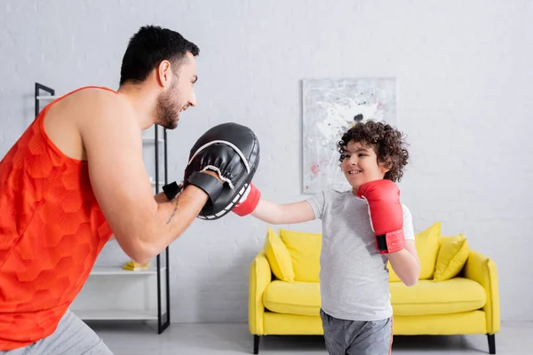 Alegre musulmán chico boxeo con padre en casa - foto de stock