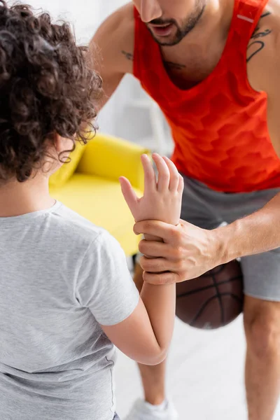 Man teaching son while holding basketball on blurred background at home — Stock Photo
