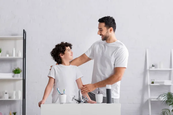 Cheerful arabian father hugging son in bathroom — Stock Photo