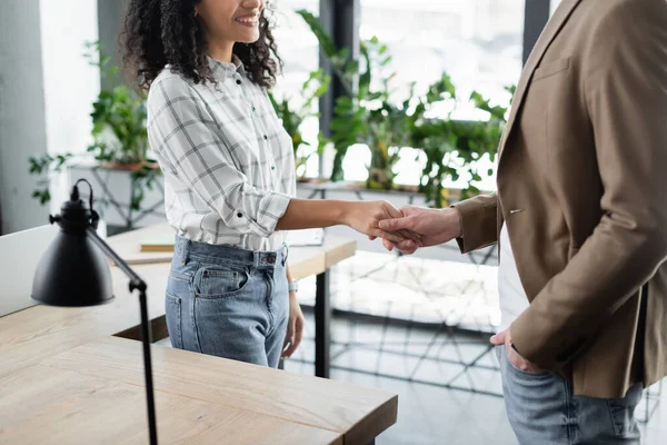 Cropped view of smiling african american businesswoman handshaking with colleague — Stock Photo