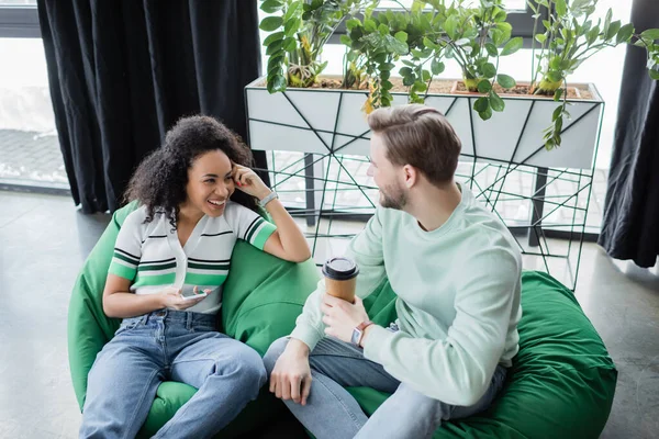 Excited african american woman with smartphone talking to business partner in lounge zone — Stock Photo