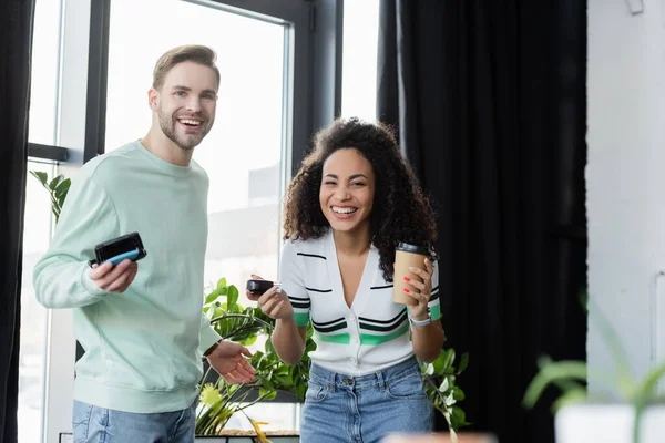 Felices colegas de negocios interracial mirando a la cámara mientras sostiene sellos automáticos - foto de stock