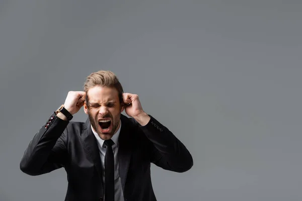 Angry businessman showing clenched fists and shouting isolated on grey — Stock Photo