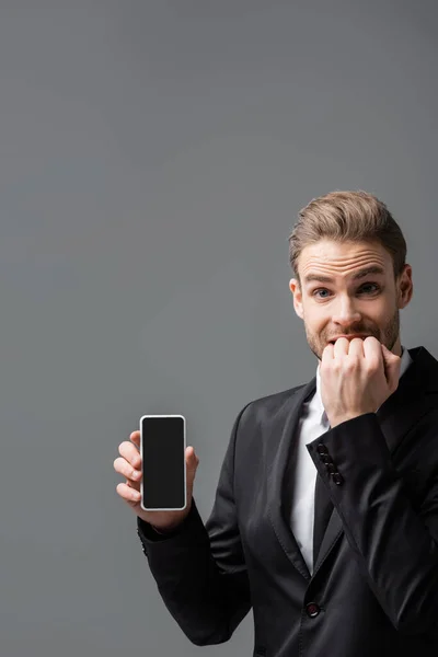 Worried businessman showing mobile phone with blank screen isolated on grey — Stock Photo