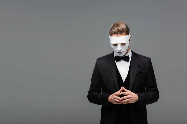 Homem de negócios na máscara facial de pé com os dedos unidos isolados em cinza — Fotografia de Stock