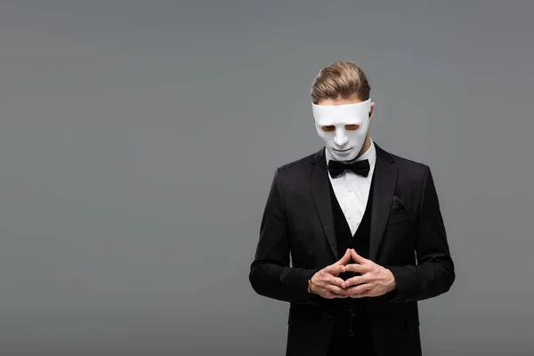 Hombre de negocios con mascarilla de pie con los dedos unidos aislados en gris - foto de stock