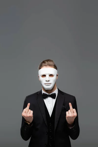 Businessman in face mask showing middle fingers isolated on grey — Stock Photo