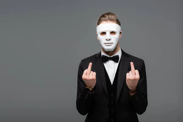 Businessman showing middle fingers while wearing face mask isolated on grey — Stock Photo