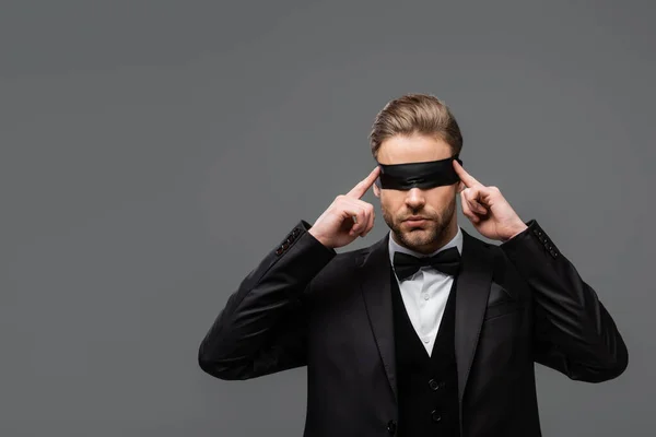 Elegant businessman adjusting blindfold isolated on grey — Stock Photo