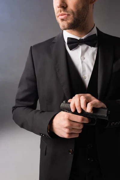 Vista recortada de elegante hombre de negocios sosteniendo pistola sobre fondo gris con humo - foto de stock