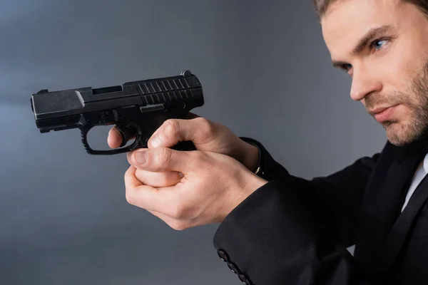 Young businessman aiming with gun on grey background with smoke — Stock Photo