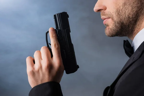 Vista recortada de joven empresario con pistola sobre fondo gris con humo - foto de stock