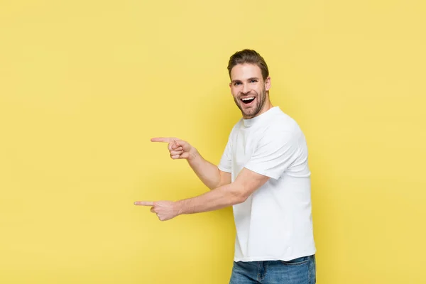 Взволнованный мужчина смотрит на камеру, указывая пальцами на желтый цвет — стоковое фото