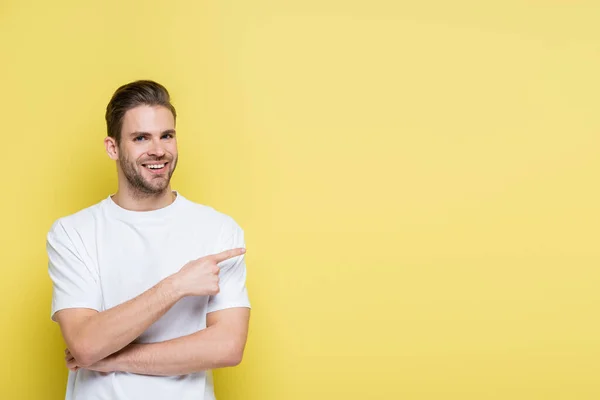 Cheerful man looking at camera while pointing with finger on yellow — Stock Photo