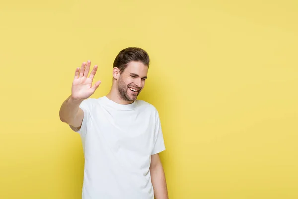 Homem alegre com olhos fechados mostrando gesto de recusa no amarelo — Fotografia de Stock