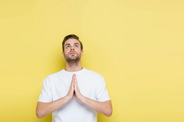 Young man looking up while showing hope gesture on yellow — Stock Photo