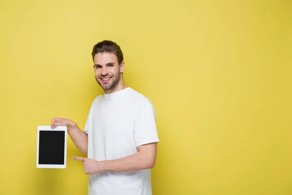 Pleased man pointing at digital tablet with blank screen on yellow — Stock Photo