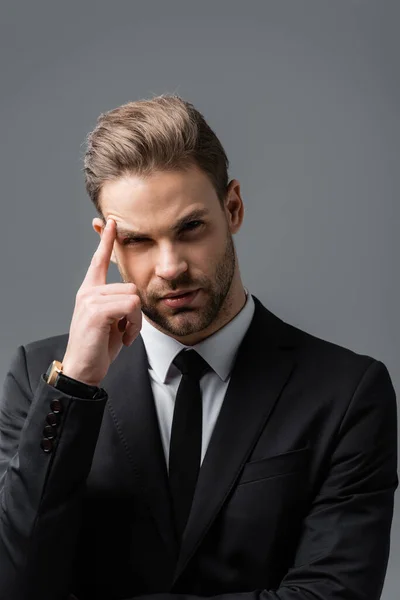 Thinking businessman touching head and looking at camera isolated on grey — Stock Photo