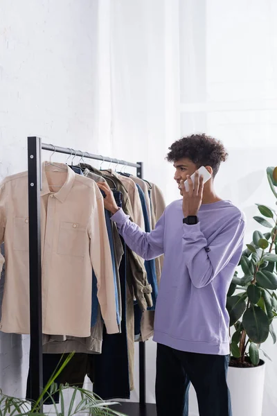 Африканский американский шоурум, говорящий на смартфоне возле вешалки — Stock Photo