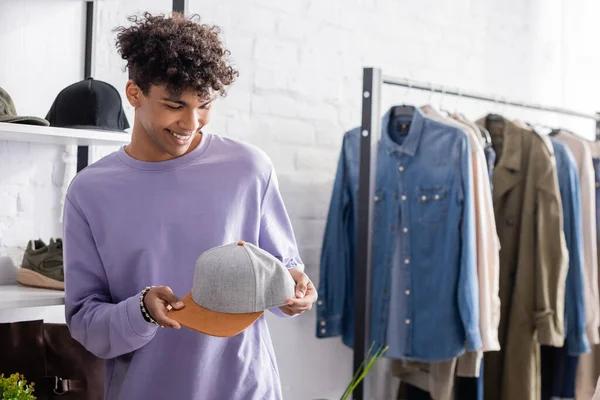 Fröhlicher afrikanisch-amerikanischer Geschäftsmann mit Mütze im Showroom — Stockfoto