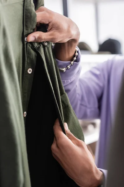 Vue recadrée du propriétaire afro-américain de la chemise touchante du showroom au premier plan flou — Photo de stock