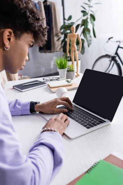 Laptop com tela em branco perto de empresário afro-americano em primeiro plano desfocado trabalhando no showroom — Fotografia de Stock