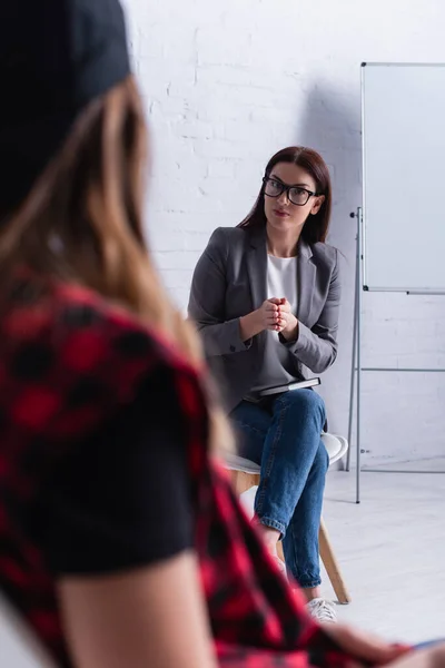 Psychologist in glasses consulting teenage girl on blurred foreground — Stock Photo