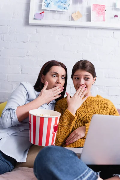 Adolescente ragazza e madre guardando film spaventoso sul computer portatile in camera da letto — Foto stock