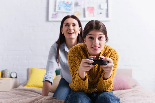 KIEW, UKRAINE - 20. NOVEMBER 2020: Teenager-Mädchen hält Steuerknüppel neben aufgeregter Mutter auf verschwommenem Hintergrund — Stockfoto