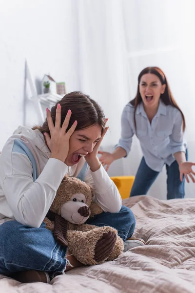 Teenage girl screaming near angry mother on blurred background — Stock Photo