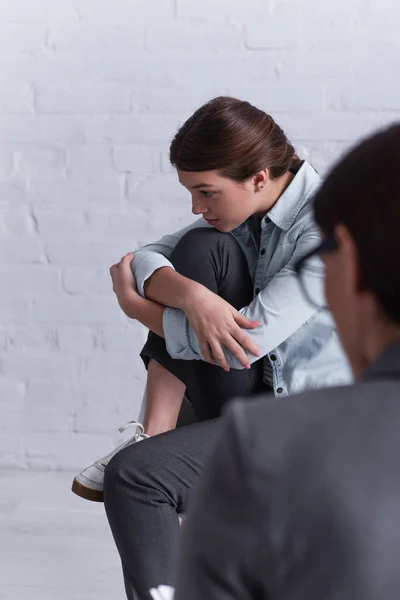 Worried teenage girl sitting near psychologist on blurred foreground — Stock Photo
